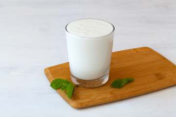 glass of milk with green mint on white background. fresh dairy drink. healthy, fermented products concept. Copy space. Kefir, yogurt or Lassi drink with probiotics on the table. Indian cuisine.
