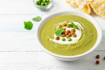 Green pea vegetable soup puree on wooden background. Copy space.