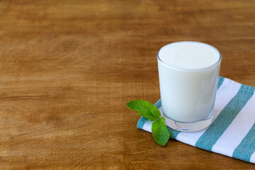 Lassi drink with green mint in glass on wooden background. Probiotic cold dairy drink. healthy, fermented products concept. Copy space. Kefir, milk or yogurt with probiotics. Indian cuisine