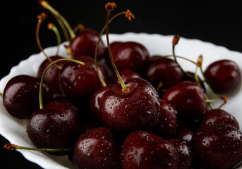 Ripe cherries background. Ripe juicy cherries on a white plate.
