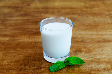 glass of Lassi drink with green mint in glass on wooden background. Probiotic cold dairy drink. healthy, fermented products concept. Copy space. Kefir, milk or yogurt with probiotics. Indian cuisine