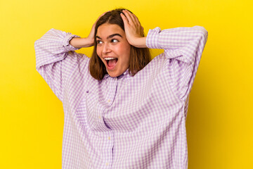 Young caucasian woman isolated on yellow background screaming, very excited, passionate, satisfied with something.