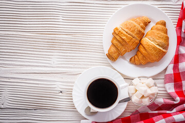 delicious fresh croissant and cup of coffee on a white wooden rustic background