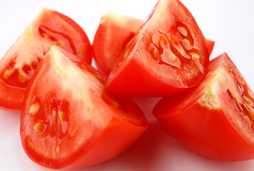 Pieces of sliced ripe red tomato on a white background.