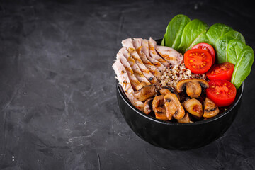 bowl of healthy quinoa with grilled chicken and vegetables on a dark rustic background