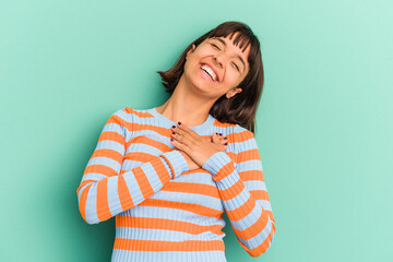 Young mixed race woman isolated on blue laughing keeping hands on heart, concept of happiness.