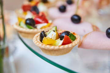Buffet at the event. An assortment of snacks on a glass plate. Banquet hall, restaurant. Food, snacks with vegetables, salad in a tartlet