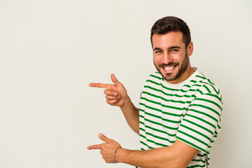 Young caucasian man isolated on white background pointing with forefingers to a copy space,...