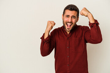 Young caucasian man isolated on white background raising fist after a victory, winner concept.