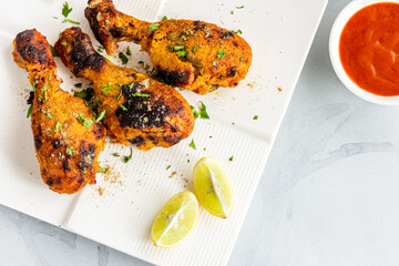 Grilled Chicken Drumsticks Garnished with Fresh Cilantro and Lemon Top Down Horizontal Close Up Photo