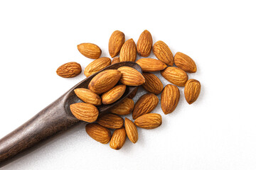 The almonds are in a brown wooden spoon and several seeds around which are on isolate a white background.