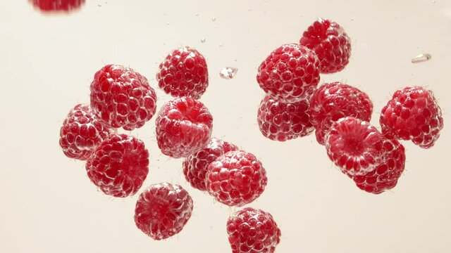 Raspberry splash falling into water, white background, aqua silver bubble drops