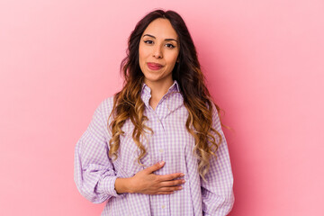 Fototapeta premium Young mexican woman isolated on pink background touches tummy, smiles gently, eating and satisfaction concept.