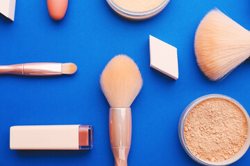 Decorative cosmetics and makeup brushes on color background