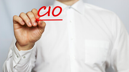 A businessman in a white shirt writes a text CIO on a white background with a red marker . business concept