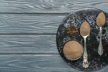 Board with black pepper powder and peppercorns on dark wooden background