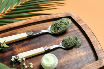 Board with henna powder and jar of cream on color background, closeup