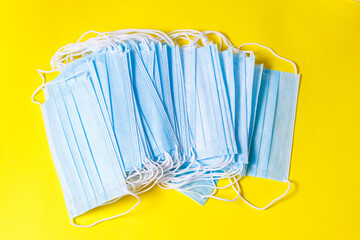 Many blue medical masks on yellow background