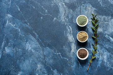 Bowls with henna powder on color background