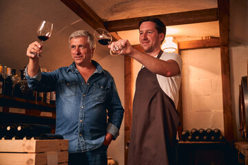 Smiling male Caucasians looking at the color of wine in cellar