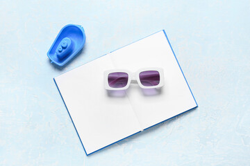 Stylish sunglasses, open book and toy boat on color background