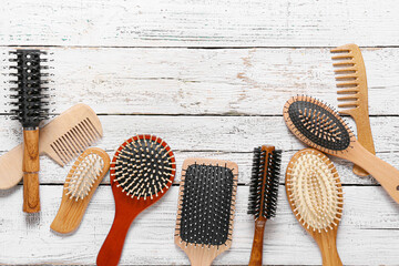 Different hair brushes and combs on light wooden background