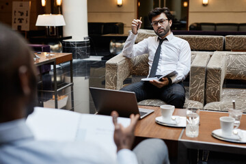 Portrait of two business people working at table in hotel lounge
