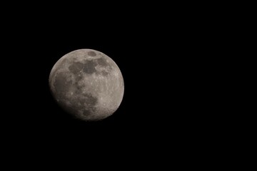A close up portrait of the moon surrounded by the darkness and emptiness of space. The craters and other details of the only natural satellite of earth are clearly visible.