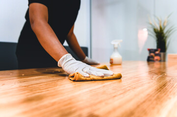 Hand of waiter woman cleaning table with disinfectant spray and microfiber cloth for disinfecting at indoor restaurant. Coronavirus prevention concept.