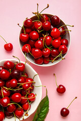 Obraz na płótnie Canvas Bowls with tasty ripe cherry on color background