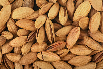 Background of unpeeled almonds in the shell. Natural background for healthy eating concept. Almonds macro.