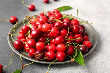 Plate with tasty ripe cherry on table