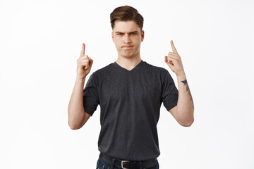 Dislike and negative emotion. Frowning young man pointing fingers up, complaining, unfair thing,...