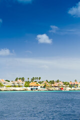 Fototapeta premium Resort hotel at the waterfront in Kraledijk, Bonaire, Dutch Antilles, Caribbean Sea, with emerald seashore and blue sky