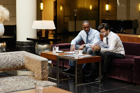 Portrait Of Two Business People Discussing Deal In Hotel Lounge, Copy Space