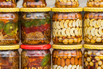 Canned nuts and candied fruit in glass jars. Homemade preservation.