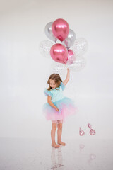 little girl in a festive dress stands with a bunch of balloons on white with a place for text