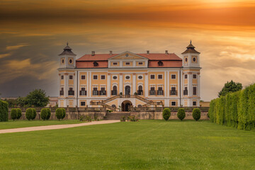 Beautiful state baroque chateau Milotice in the Czech Republic. In front of the castle is a garden. In the background is a dramatic sunset sky.