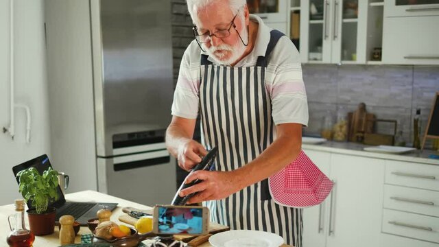 The old chef records a video tutorial on his phone about preparing mackerel fish