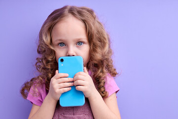 Easy app for kids.awesome little girl using smartphone, playing game on mobile device, browsing web with interested involved expression, internet addiction. indoor studio shoot, isolated