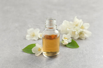 Fototapeta na wymiar Essential oil and jasmine flowers on light grey table
