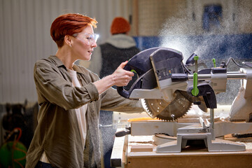 side view on young beautiful female carpenter using electric machine, enjoy woodworking, woman has...