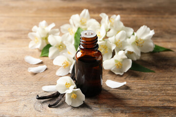 Jasmine essential oil and fresh flowers on wooden table