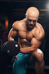 Fototapeta premium Well-shaped male athlete doing exercises with dumbbells