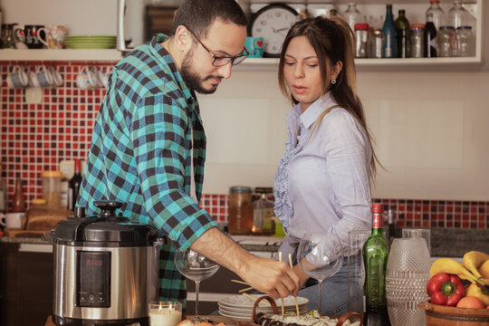 el novio le ense&ntilde;a a comer sushi a la chica mientras est&aacute;n en la cocina esperando un momento mientras llegan amigos a comer