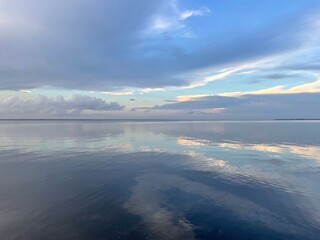 Sunset clouds reflecting onto bay water 