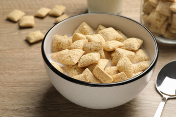 Bowl with tasty corn pads and milk on wooden table, closeup