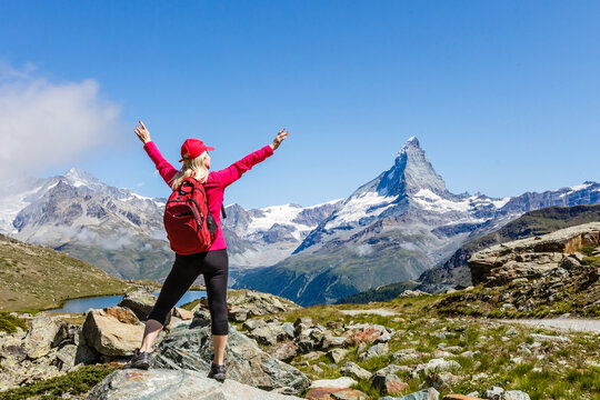Hiking in the swiss alps with flower field and the Matterhorn peak in the background.