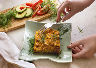 Lasagna, homemade Italian dish and fresh vegetables. Woman serving portion of homemade lasagna 