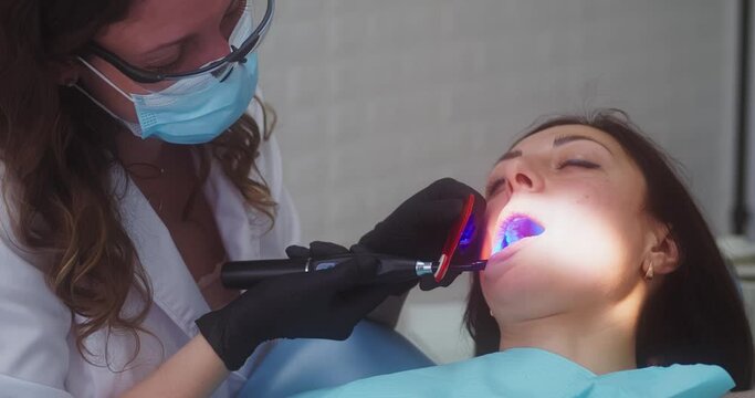 Dental polymerization lamp in dentist hand, with UV light and laser. Stomatological instrument in the dentist clinic. Medicine, health, stomatology concept.